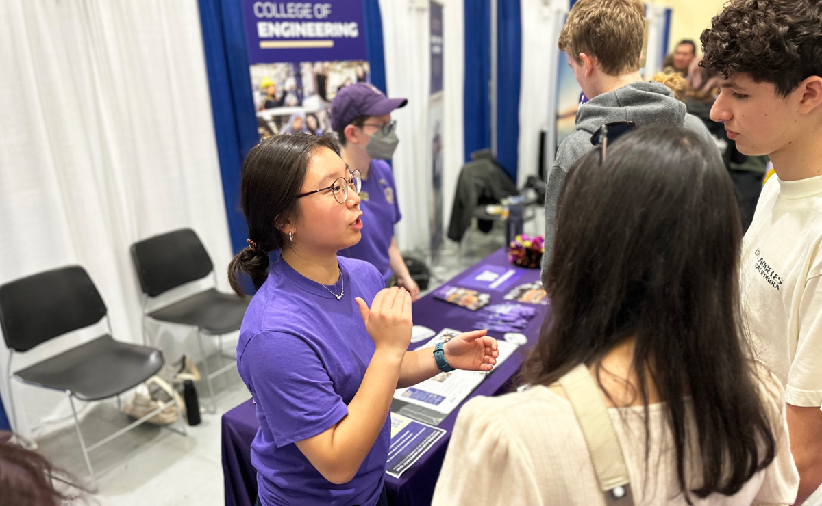 A student speaking to two people at an event