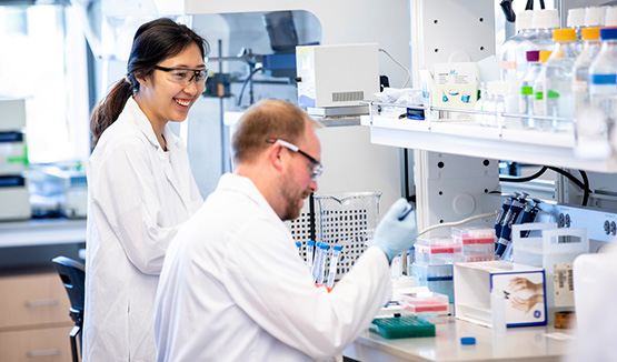 Two researchers wearing lab coats working in a lab