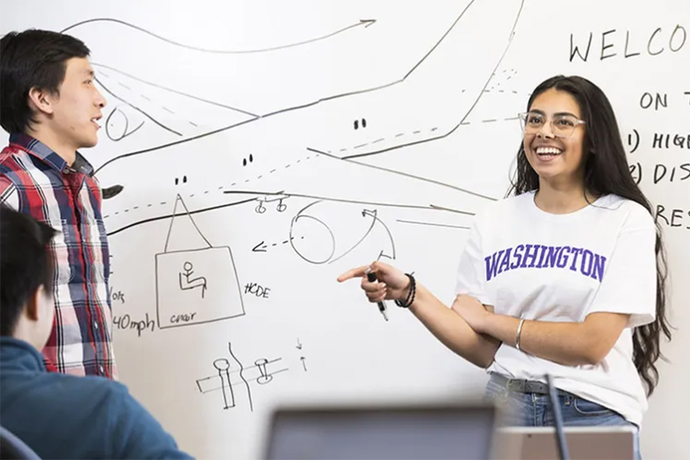 Two students brainstorming at a white board