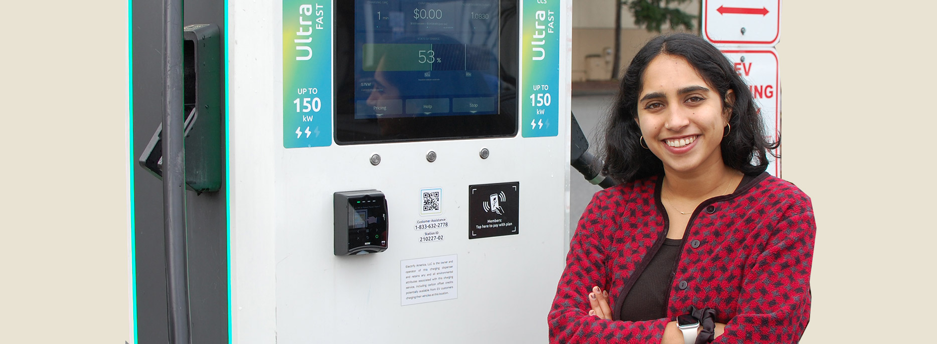 A smiling student standing next to a charging station