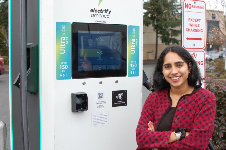 A smiling student standing next to a charging station