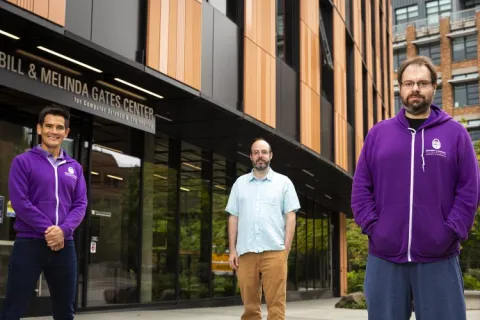 Three people stand outside in front of a building