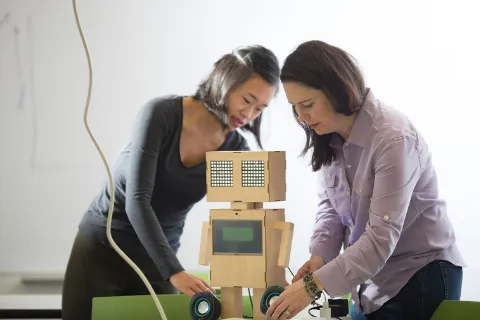 Two women putting together a robot