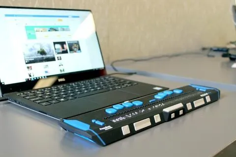 A laptop with a screen reader attached sitting on a table