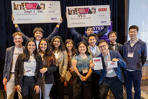 Group of students holding two big check awards