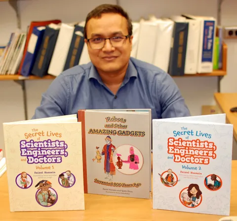 Man sitting at a desk showing three books