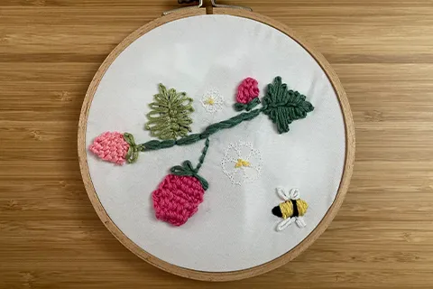 a embroidery hoop with a flower and a bee