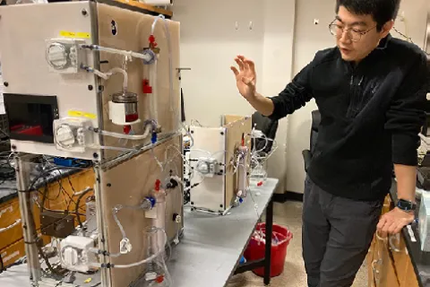 Shaohang Hao stands next to a prototype device to recover patients from multiorgan failure