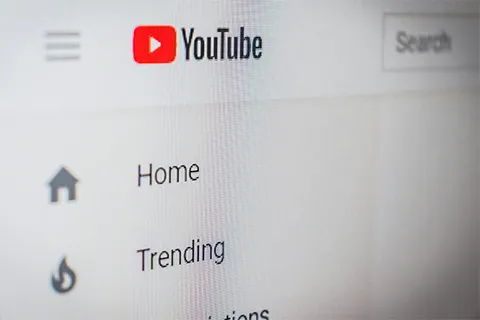 A computer screen with the YouTube logo, a red rectangle with a triangle in it, above links to Home and Trending