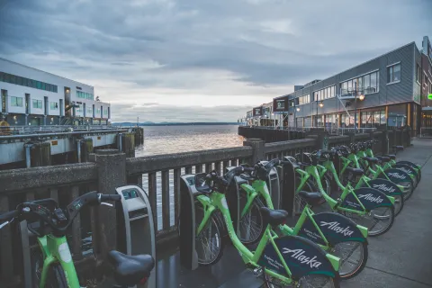 Line of Pronto bikes on a sidewalk in front of water