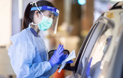 woman in scrubs gear talking to someone in a car