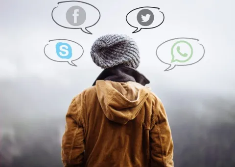 The back of a person wearing a hat and a jacket. Drawn around the person's head are four speech bubbles: Each one contains a logo for either Skype, Facebook, Twitter or WhatsApp