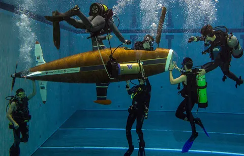 Students underwater working on submarine