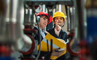 Two people wearing hardhats in a factory workplace